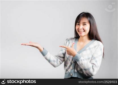 Smiling happy woman presenting product holding something on palm away side, Portrait Asian beautiful young female show hand demonstrate gesture studio shot isolated on white background with copy space