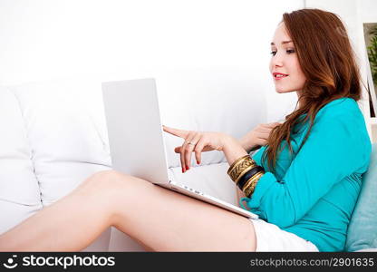 Smiling happy woman sitting on the sofa and using laptop at home