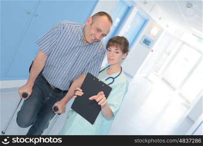 smiling healthcare worker talking with a man with crutches