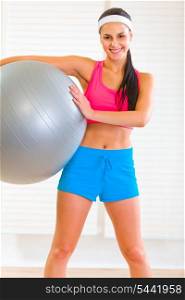 Smiling healthy girl holding fitness ball at home&#xA;