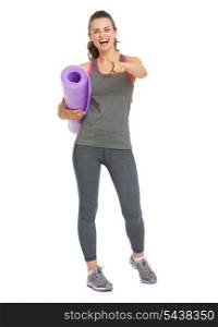 Smiling healthy young woman with fitness mat pointing in camera