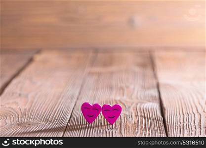 Smiling hearts on wood. Two smiling pink hearts on wooden background, relationship valentines day concept