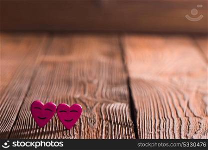 Smiling hearts on wood. Two smiling pink hearts on wooden background, relationship valentines day concept