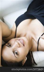 Smiling Hispanic woman lying down and looking at viewer.