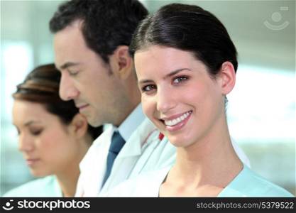 Smiling hospital nurse standing with colleagues