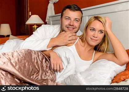 Smiling husband holding wife lying bed daydreaming married couple