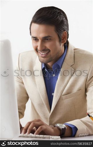 Smiling Indian businessman working on desktop PC in office