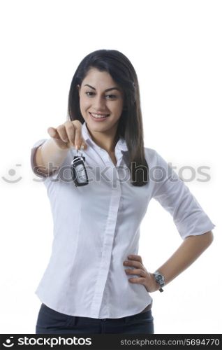 Smiling Indian businesswoman holding car keys against white background