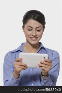 Smiling Indian businesswoman using tablet PC over white background