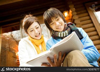 Smiling Japanese teenage couple reading