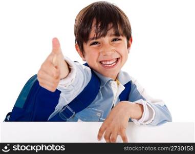 Smiling kindergarden boy showing thumbs up sign as he stands behind the white blank board on isolated background