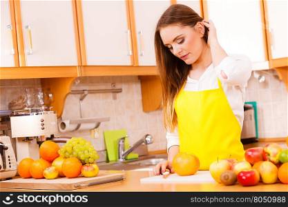 Smiling lady in kitchen.. Food cuisine diet fruit natural concept. Smiling lady in kitchen. Female cook leaning on counter next to pile of fruits and kitchenware utensils.