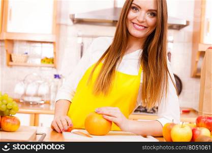 Smiling lady in kitchen.. Food cuisine diet fruit natural concept. Smiling lady in kitchen. Female cook leaning on counter next to pile of fruits and kitchenware utensils.