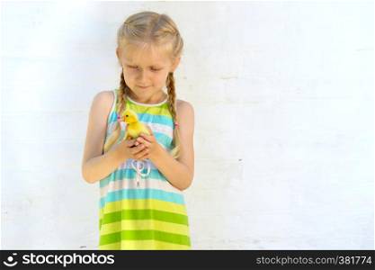 smiling little girl holding a little duckling