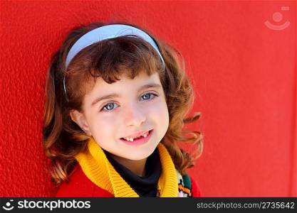 smiling little girl indented front teeth smile on red wall background