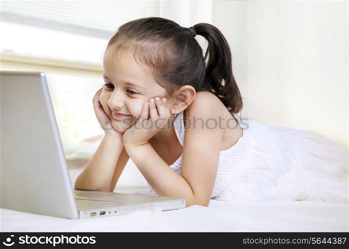 Smiling little girl looking at laptop screen