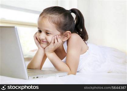 Smiling little girl looking at laptop screen