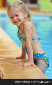 smiling little girl near the open-air swimming pool