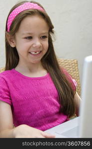 Smiling Little Girl Using a Laptop