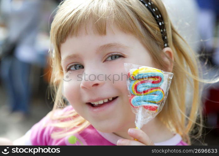 smiling little girl with lollipop sweet in hand outdoors portrait