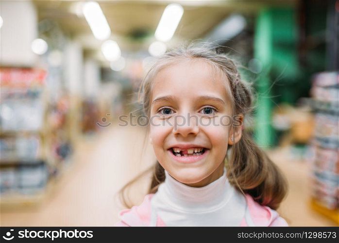 Smiling little girl without tooth, childrens happiness in pet shop. Kid customer in petshop. Smiling little girl, happiness in pet shop