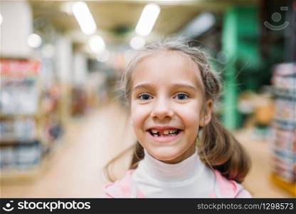 Smiling little girl without tooth, childrens happiness in pet shop. Kid customer in petshop. Smiling little girl, happiness in pet shop