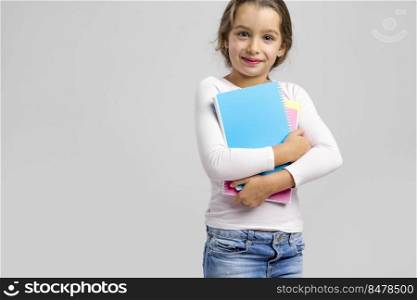 Smiling little student girl holding notebooks
