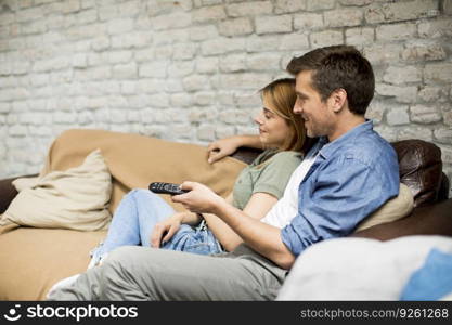 Smiling lovely young couple relaxing and watching TV at home