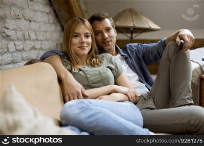 Smiling lovely young couple relaxing and watching TV at home
