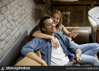 Smiling lovely young couple relaxing and watching TV at home