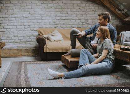 Smiling lovely young couple relaxing and watching TV at rustic home