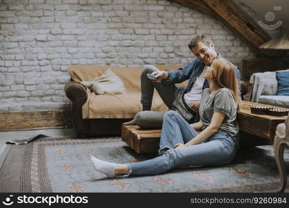 Smiling lovely young couple relaxing and watching TV at rustic home