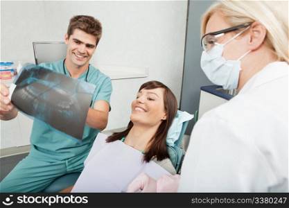Smiling male dentist explaining the details of x-ray to a beautiful female patient. Dentist explaining the details of x-ray to a female patient