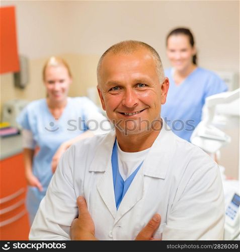 Smiling male dentist posing with female assistants at office