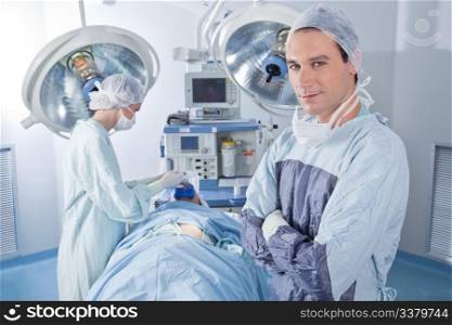 Smiling male doctor with arms crossed in operating room