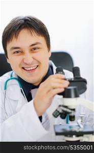 Smiling male doctor working with microscope