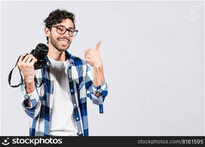 Smiling male photographer showing a camera and giving thumb up. Young man holding a camera and giving the thumb up, Smiling guy photographer showing a camera with thumb ok