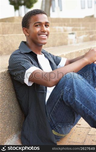 Smiling Male Teenage Student Sitting Outside On College Steps