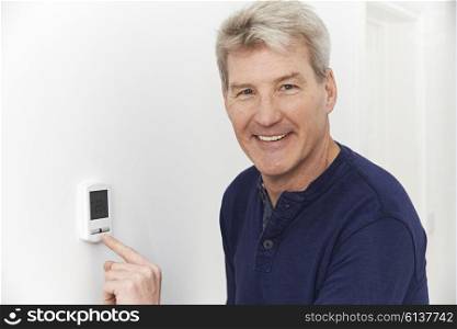 Smiling Man Adjusting Thermostat On Home Heating System
