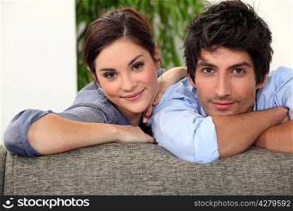 Smiling man and woman leaning on a couch