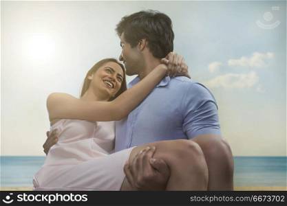 Smiling man carrying girlfriend on beach