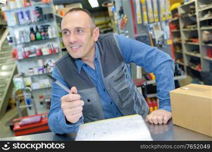 smiling man cashier standing at pay desk in household store