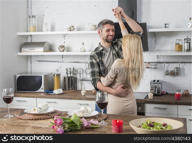 smiling man dancing with blond woman near table kitchen