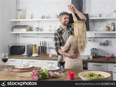 smiling man dancing with blond woman near table kitchen