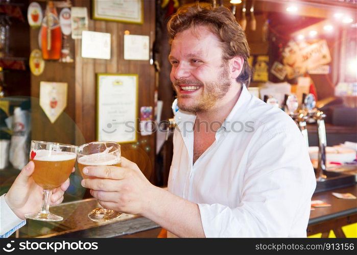 smiling man drinking a fresh beer in a pub with friend