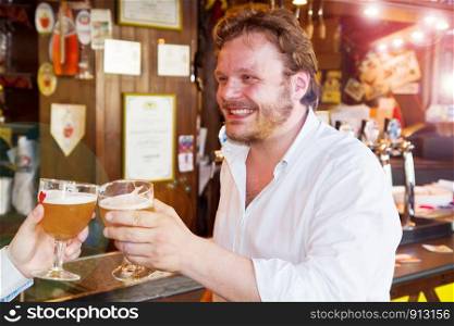 smiling man drinking a fresh beer in a pub with friend