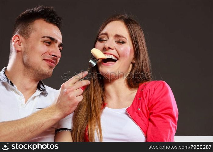 Smiling man feeding happy woman with banana. Wife and husband eating fruit. Healthy nutrition, dieting and slimming concept.