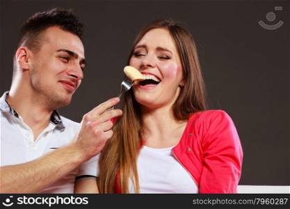 Smiling man feeding happy woman with banana. Wife and husband eating fruit. Healthy nutrition, dieting and slimming concept.