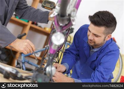 smiling man fixing bike wheel in sport store