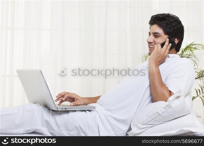 Smiling man having conversation while using laptop at home
